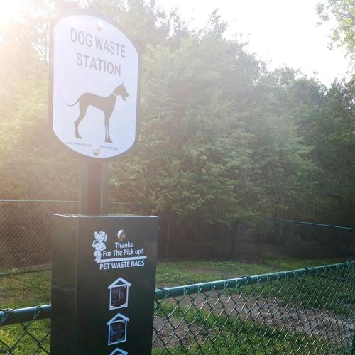 a dog waste station sign in front of a fence at Anvil Campground in Williamsburg