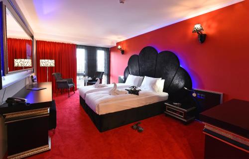 a bedroom with a large bed with a red wall at Best Boutique Hotel in Stara Zagora