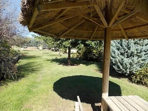 a wooden bench under a wooden umbrella in a yard at Domaine De La Bégude in Fayence