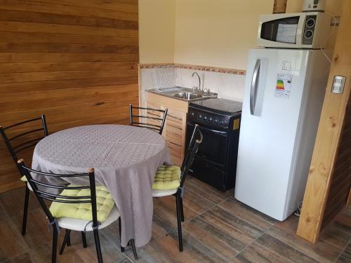 a kitchen with a table and a white refrigerator at Cabañas Torre Huillinco in Huillinco
