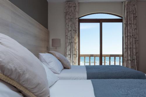 a bedroom with two beds and a large window at Hotel y Cabañas Campanario in La Serena