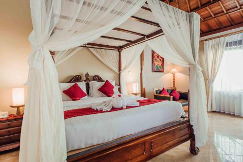 a bedroom with a canopy bed with red and white pillows at Kuta Puri Bungalows, Villas and Resort in Kuta