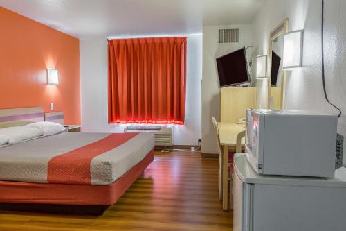 a hotel room with a bed and a red curtain at Motel 6-Redmond, OR in Redmond