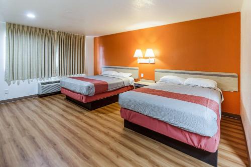 duas camas num quarto de hotel com paredes cor de laranja em Motel 6-Lancaster, TX - DeSoto - Lancaster em Lancaster