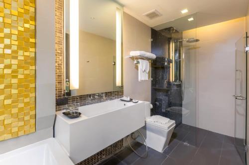 a bathroom with a bath tub, toilet and sink at The Charm Resort Phuket - SHA Certified in Patong Beach