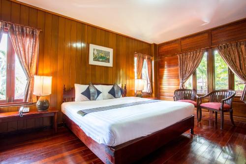 um quarto com uma cama grande, paredes e janelas de madeira em Nova Samui Resort em Chaweng