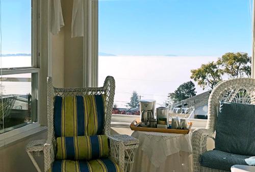 ホワイトロックにあるStar of the Sea guest houseの椅子2脚、テーブル、窓が備わる客室です。