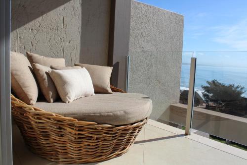 una silla de mimbre en un balcón con vistas al océano en Seafront Apartment in Mossel Bay en Mossel Bay