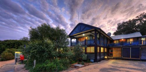 a large house with a cloudy sky behind it at Fraser Island Retreat in K'gari Island (Fraser Island)