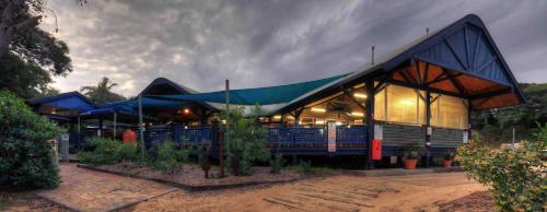 a building with a blue roof with plants in front at Fraser Island Retreat in Fraser Island