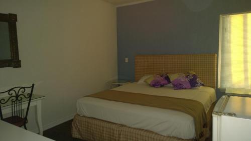 a bedroom with a bed with purple pillows on it at Solari Casa de Huespedes in Rosarito