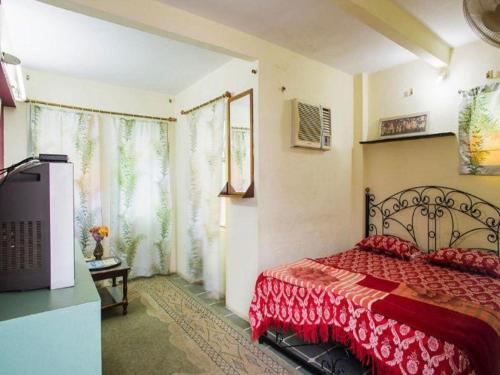 a bedroom with a bed with a red blanket and a tv at Jag Niwas Guest House & pure veg restaurant in Udaipur