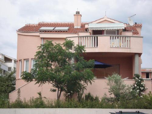 a pink house with a balcony on top of it at Apartments Eja in Zadar