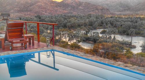 a swimming pool with a chair and a view of a river at Kapika Waterfall Lodge in Epupa