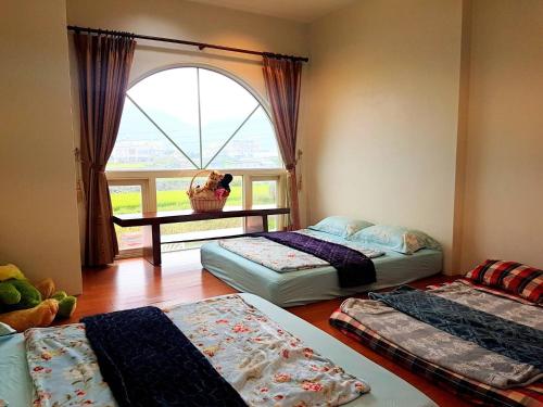 a room with three beds in front of a window at Emerald Grange in Gongguan