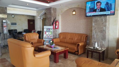 una sala d'attesa con mobili in pelle e TV di Nizwa Hotel Apartments a Nizwa