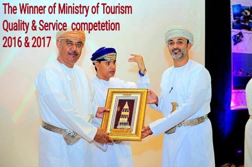a group of three men holding up a plaque with a trophy at Al Reem Chalet in Al Ashkharah