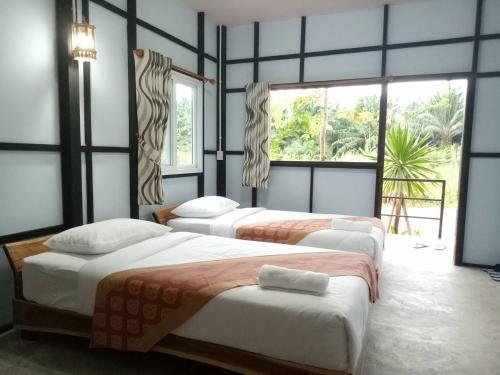 three beds in a room with two windows at Suankafae Resort สวนกาแฟรีสอร์ท in Suratthani