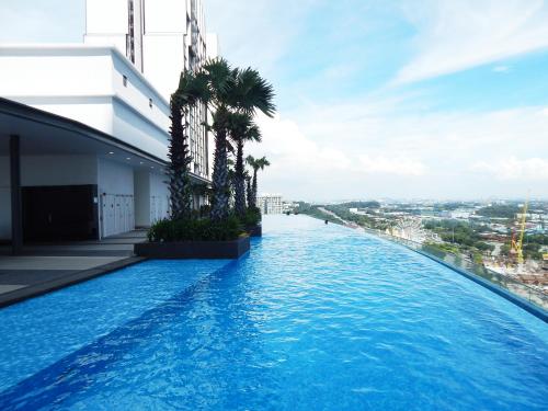 a swimming pool on top of a building with palm trees at Wadi Iman Suites @ i-City in Shah Alam