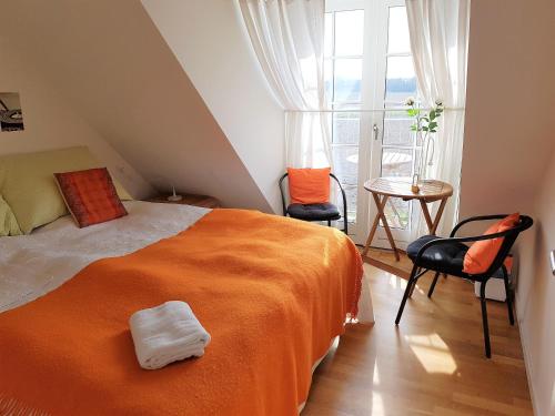 a bedroom with a bed with an orange blanket and chairs at Roskilde B&B in Gadstrup