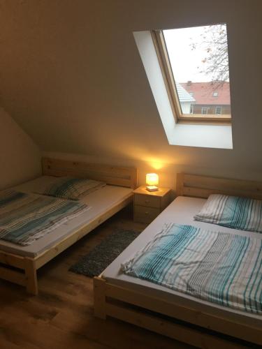 2 łóżka pojedyncze w pokoju z oknem w obiekcie FeWo s Runde Wiese RW w mieście Greifswald