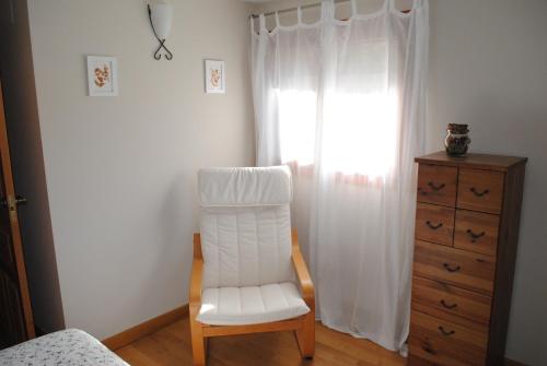 1 dormitorio con silla blanca y vestidor en Casa Los Ardos, en Poyales