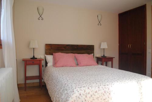 1 dormitorio con 1 cama con almohadas rosas y 2 lámparas en Casa Los Ardos, en Poyales