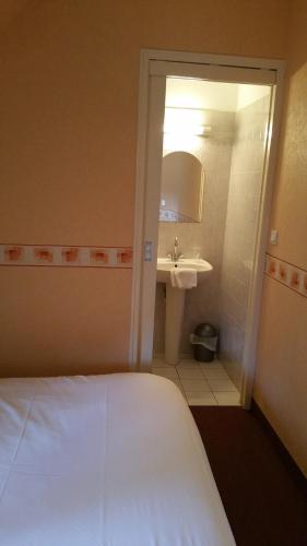une chambre avec un lit et une salle de bain avec un lavabo dans l'établissement Le Grillon, à Pontorson