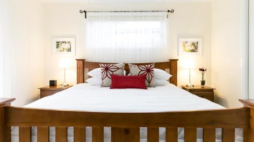 ein Schlafzimmer mit einem großen weißen Bett mit roten Kissen in der Unterkunft One Tree Accommodation in Auburn