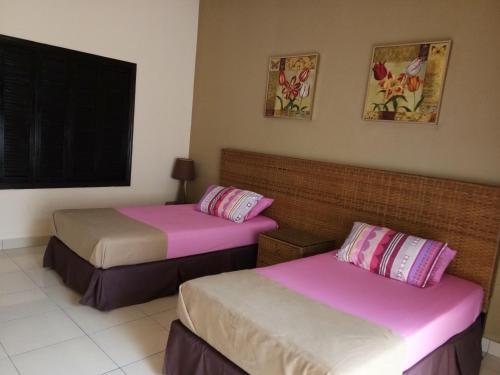 two beds in a room with pink and white sheets at Qastury Gold Coast Morib Resort in Morib