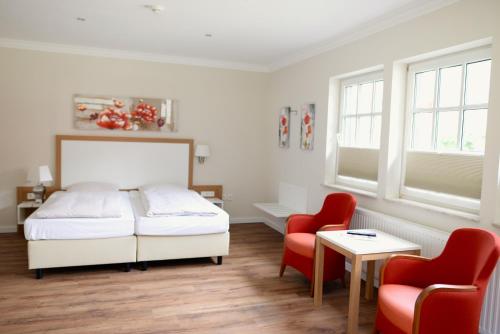 a bedroom with a bed and two red chairs at Gut Altona in Dötlingen