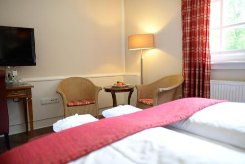 a hotel room with a bed and chairs and a television at Gut Altona in Dötlingen