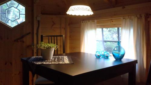 una mesa de comedor con un jarrón azul y una ventana en Pieni Talo, en Bakhuizen