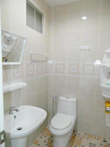 a white bathroom with a toilet and a sink at Garden Place in Phetchabun
