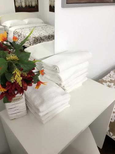 Vacation Venice Rooms في ميستر: طاولة عليها مناشف بيضاء و إناء من الزهور