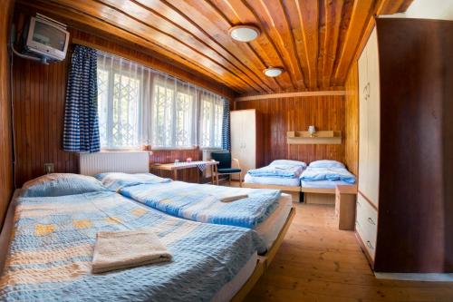 two beds in a room with wooden ceilings at Chata Advokátka in Janske Lazne