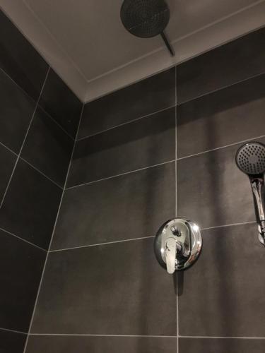 una doccia con soffione cromato su una parete piastrellata di Apartament Akademicka a Zamość