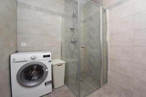 y baño con ducha y lavadora. en Ritos Apartamentai Palangoje en Palanga