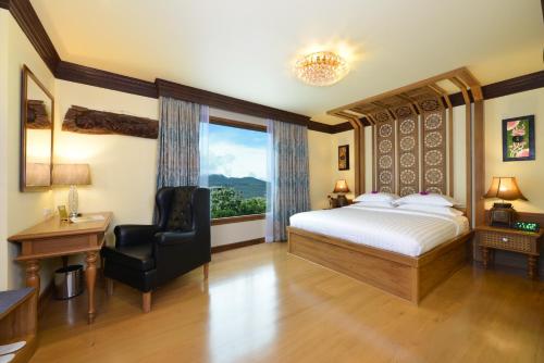 a bedroom with a bed and a chair and a window at Peak Nimman Prestige Hotel in Chiang Mai