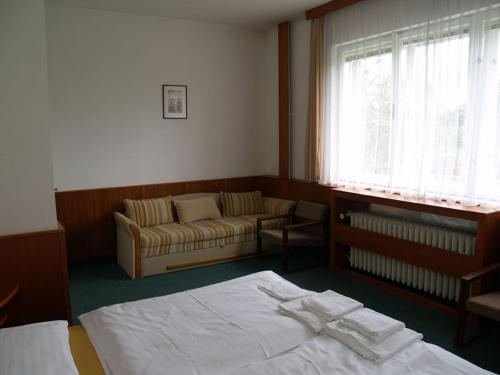 a bedroom with a bed and a couch and a window at Pension Pod Šibeňákem in Strmilov