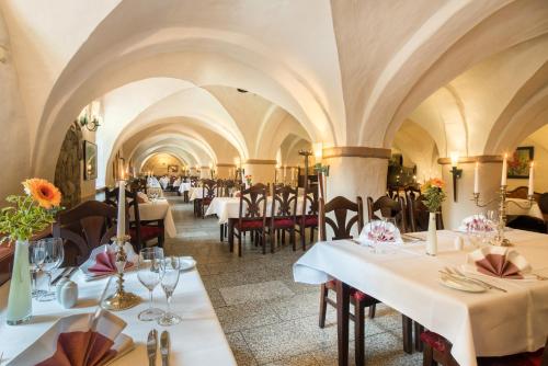 a restaurant with white tables and chairs and ceilings at Schlosshotel Klaffenbach in Chemnitz