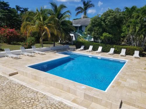 a swimming pool with lounge chairs and a house at White Sands Negril in Negril