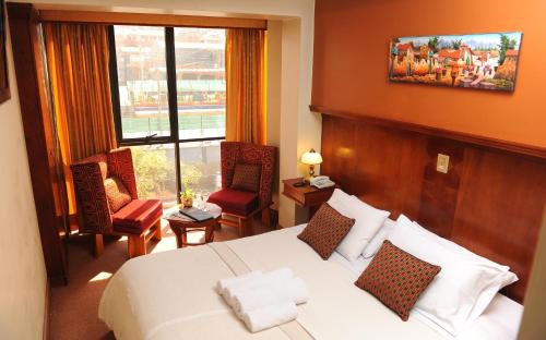 Habitación de hotel con cama, sillas y ventana en Hotel Waynapicchu, en Cusco
