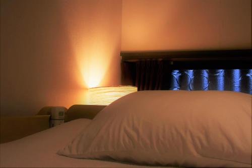 a bed with a white pillow and a lamp at Guest House Oumi in Kyoto