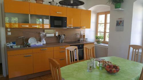 a kitchen with orange cabinets and a table with a bowl of fruit at Privatzimmer Dimitrova in Ulrichsberg