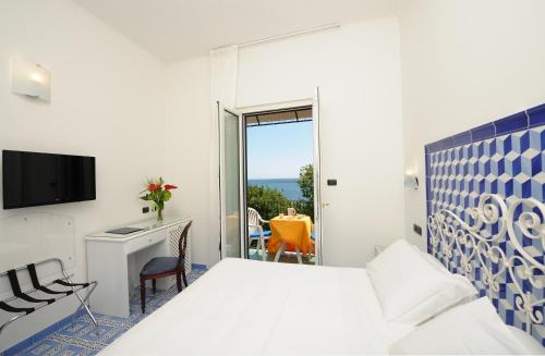 a bedroom with a bed and a desk and a window at Hotel Aurora in Amalfi