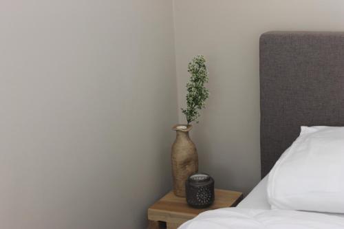 a vase with a plant on a table next to a bed at Zon Zee Zoutelande in Zoutelande