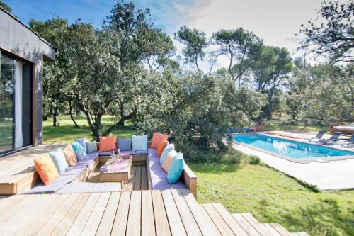 eine Terrasse mit einer Couch mit Kissen neben dem Pool in der Unterkunft Sweet lodges Aix en Provence in Rognes