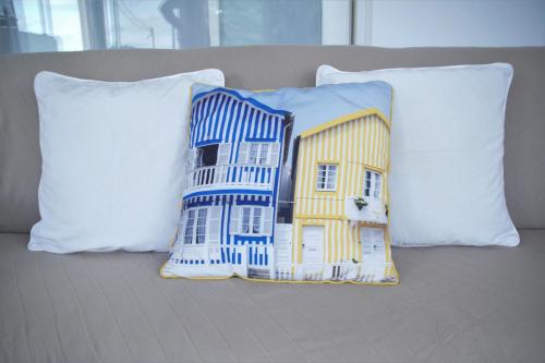a pillow with a house on it sitting on a couch at Porto Santo - Pedras Pretas Beach House in Porto Santo