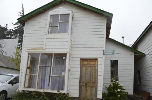 a white house with a door and a window at Cabañas Hecmar in Pichilemu